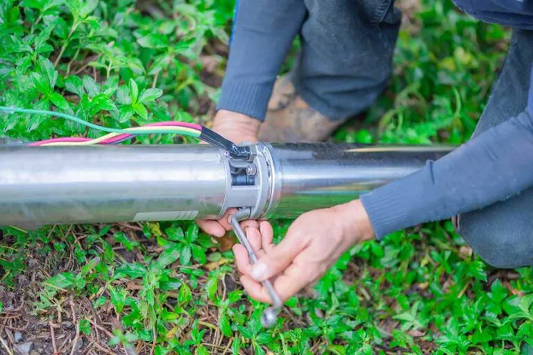 An irrigation service person's hands using a tool to repair a lawn sprinkler irrigation pump.