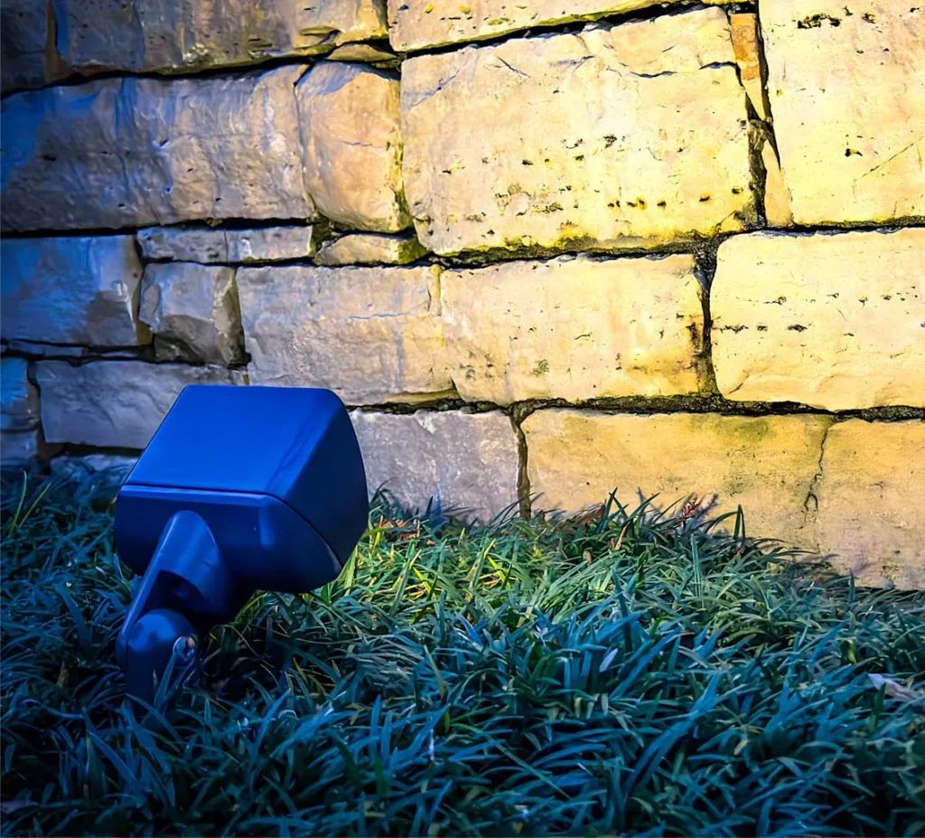 Outdoor lights illuminating a retaining wall in a residential landscape.