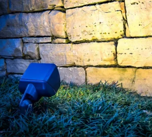 Outdoor lights illuminating a retaining wall in a residential landscape.